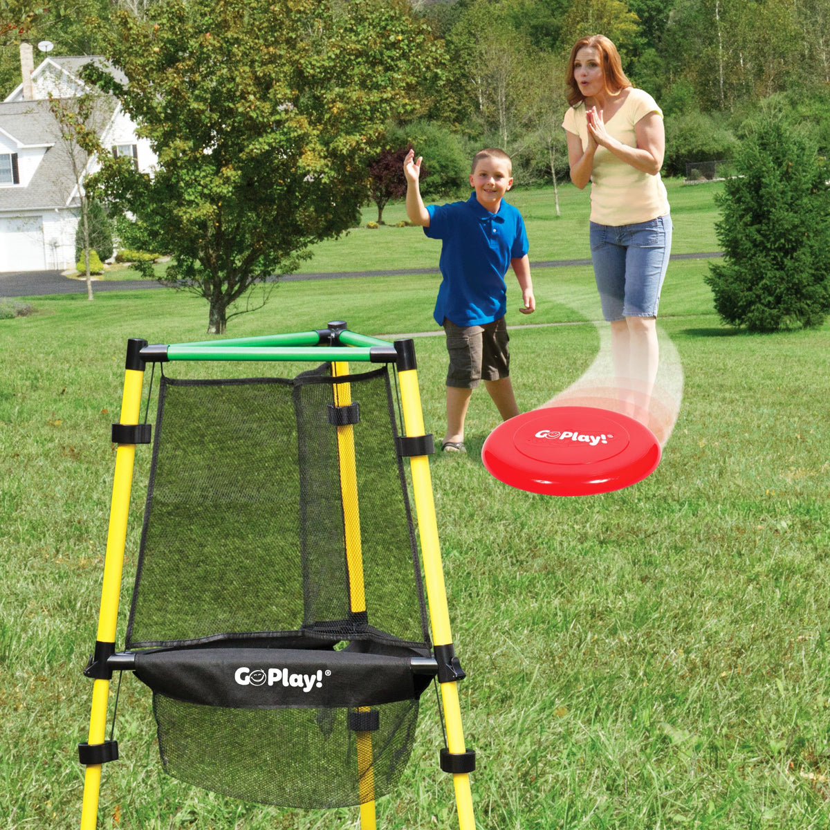 A boy and a woman playing Go Play! disc golf on grass, with a red flying disc heading towards a net target
