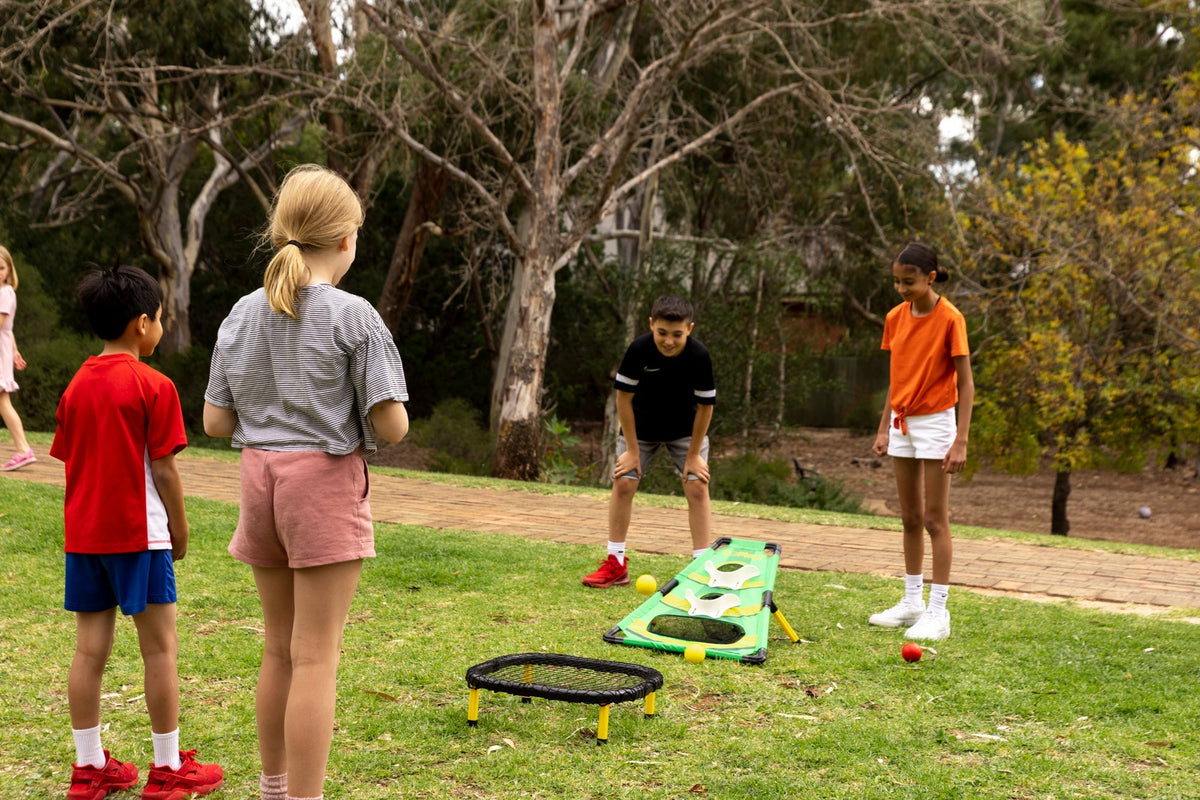 Children playing Go Play! 4-in-1 Rollin Rebounder on grass with a green scoring target, rebound net, and coloured balls