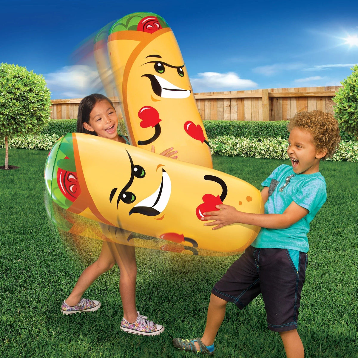 Two children playing with a large inflatable burrito toy outdoors.