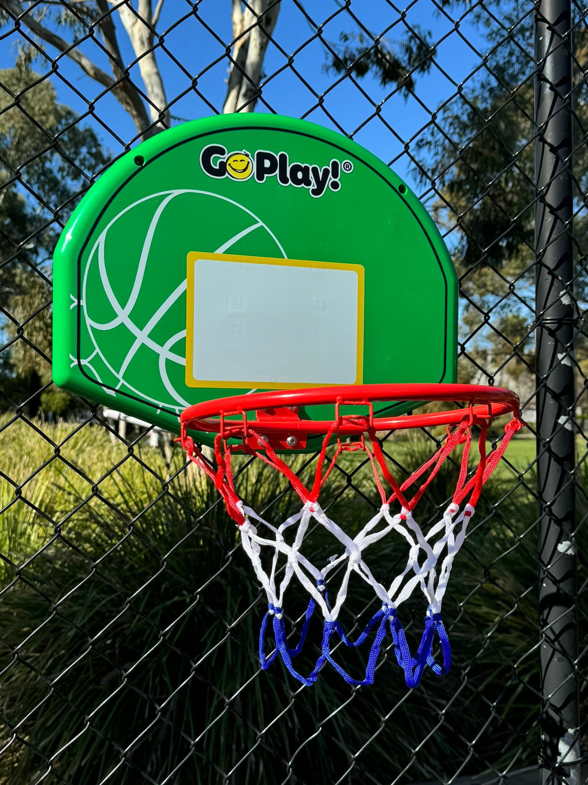 Image of basketball backboard and hoop attached to a fence