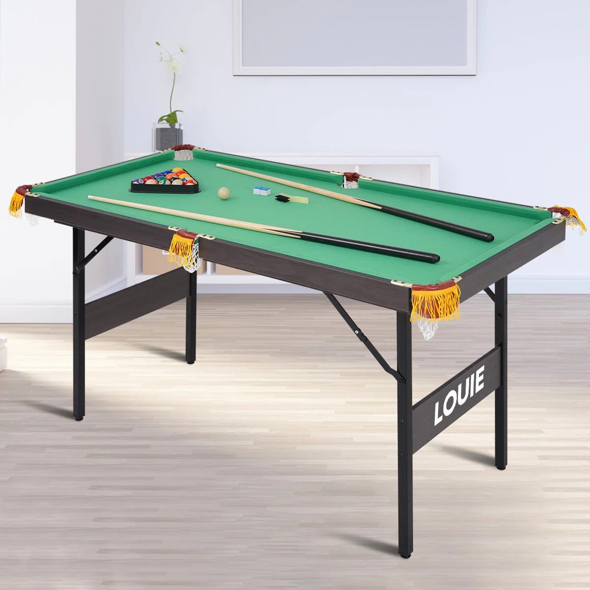 LOUIE foldable snooker pool table with green felt, black frame and folding legs, shown with 2 cue sticks, billiard balls in a triangle rack, chalks and a brush
