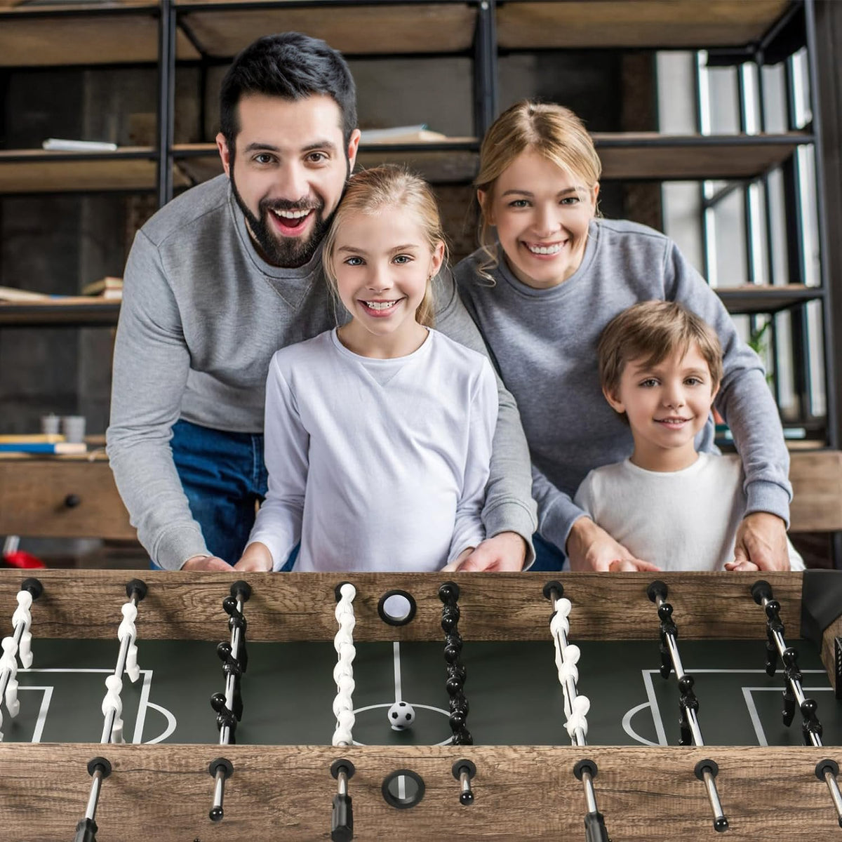 Family of four with kids playing foosball on the LOUIE table in a living room